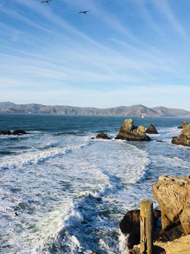 A beautiful scenery of a lot of rock formations near the sea surrounded by high mountains