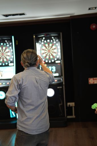 A vertical shot of a man playing darts at an amusement arcade