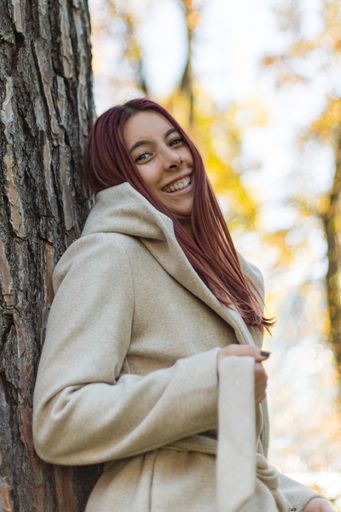 A vertical shot of a beautiful Caucasian girl wearing a coat in a park during daylight