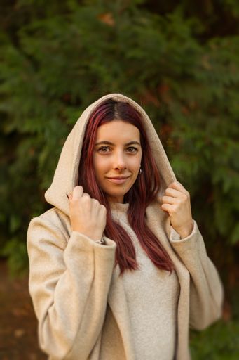 A vertical shot of a beautiful Caucasian girl wearing a coat in a park during daylight