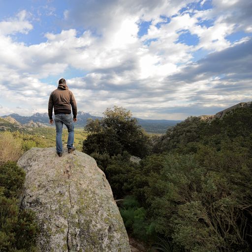 A back view of a male hiker looking at the view from a peak