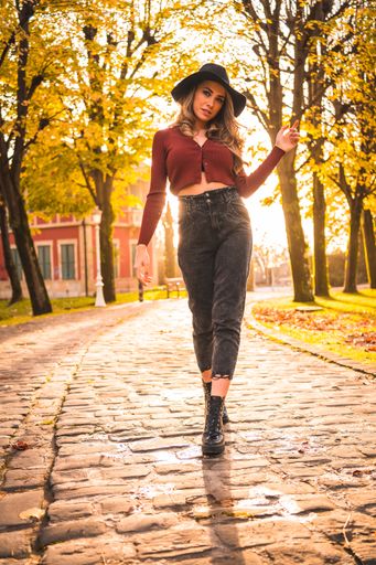 A vertical shot of a blonde Caucasian attractive woman wearing a hat posing in the park