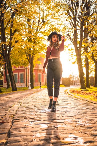 A vertical shot of a blonde Caucasian attractive woman wearing a hat posing in the park with