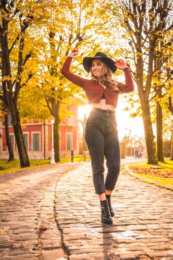A blonde Caucasian attractive woman wearing a hat posing in the park with the sun shining