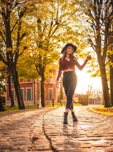 A blonde Caucasian attractive woman wearing a hat posing in the park with the sun shining