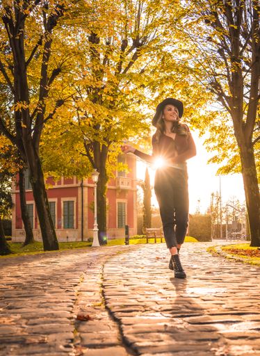 A blonde Caucasian attractive woman wearing a hat posing in the park with the sun shining