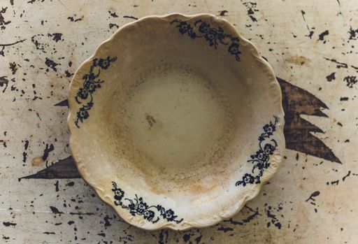 A ceramic bowl with floral designs on an old wooden table under the lights