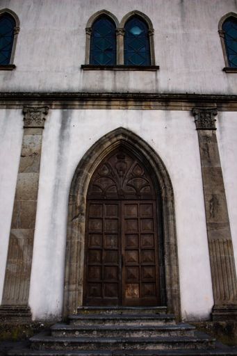 A vertical shot of a the facade of an old building with a wooden ornate door
