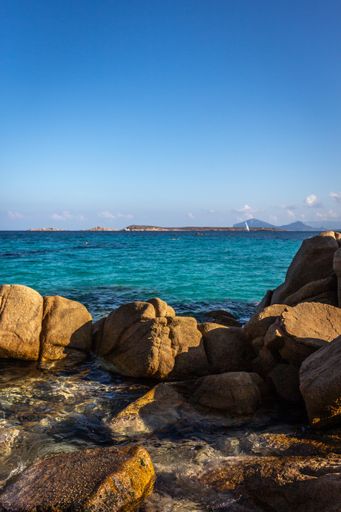 A vertical shot of a rocky beach and the blue sea