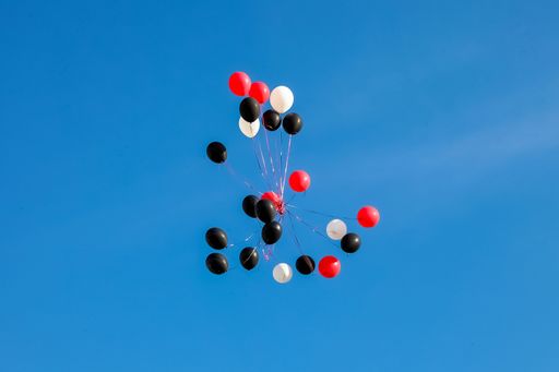 A low angle shot of flying balloons under the blue sky