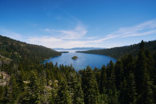 A high angle shot of the sea surrounded by a lot of fir trees and mountains