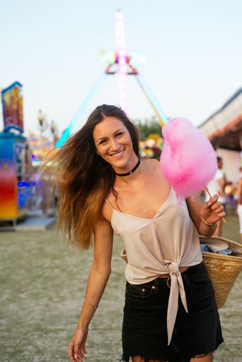 A beautiful Caucasian woman smiling and holding a cotton candy at the amusement park