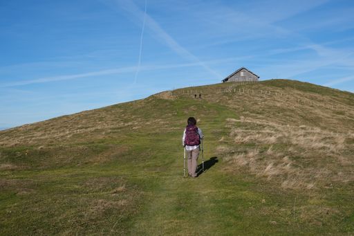 An adventurous female hiking on a hill under the blue sky in Central Switzerland
