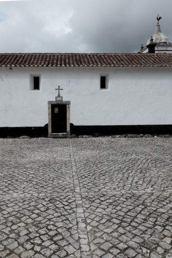 A vertical shot of a beautiful white building on a paved street under the cloudy sky