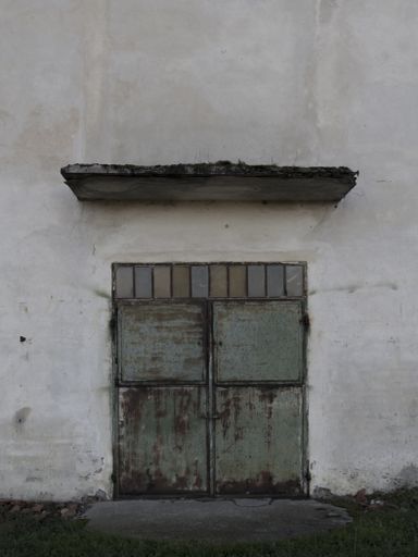 A vertical shot of the old door of a white concrete building
