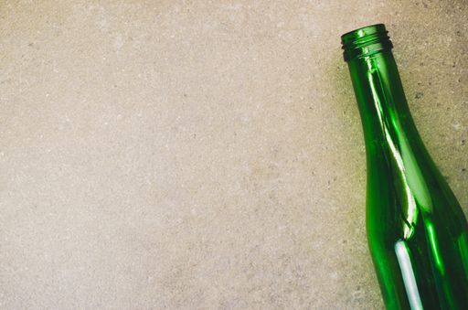 A high angle shot of an empty bottle on a rough surface
