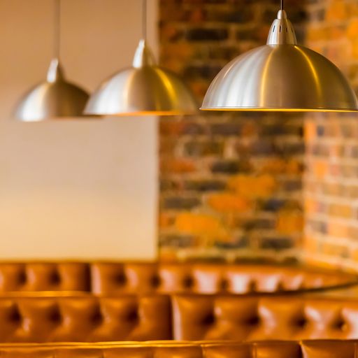 A selective focus shot of brown leather restaurant sofa with hanging stainless steel ceiling lamps