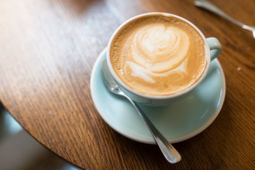 A high angle shot of a cup of cappuccino on a wooden surface