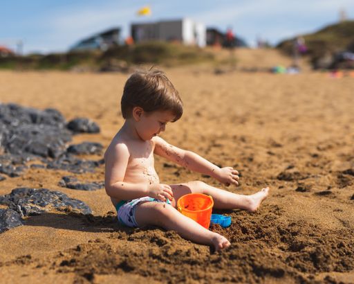 A shallow focus of an adorable little boy playing with his toys on the sandy beach