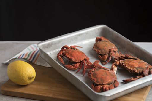 A closeup shot of red crabs on a metal oven dish on a kitchen table