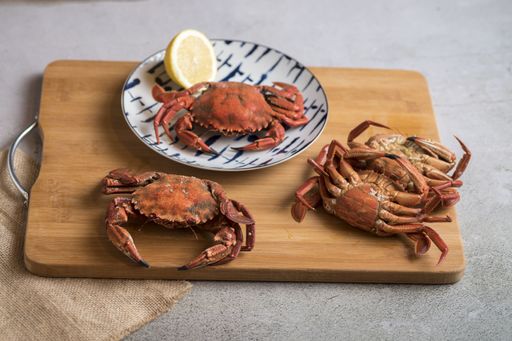 The deliciously cooked crabs on plates with lemons and herbs