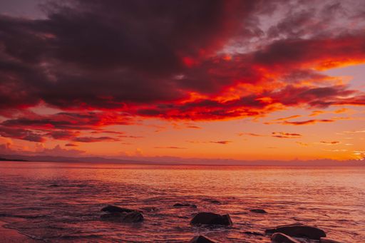 A beautiful view of a red sunset with dense clouds floating over the calm sea