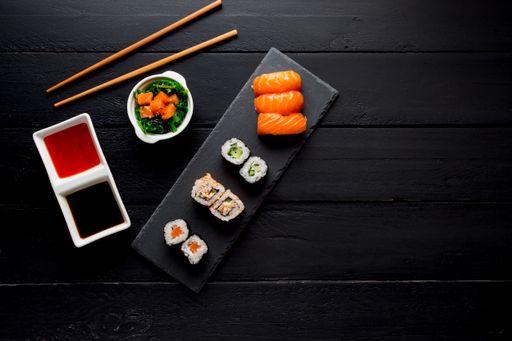 A top view of sushi and roll assortment on wooden dark background