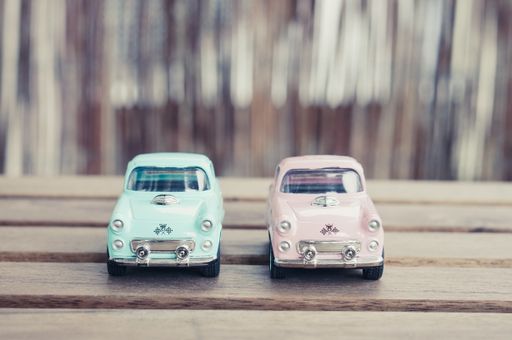 Pink and blue classic toy model cars on a wooden table