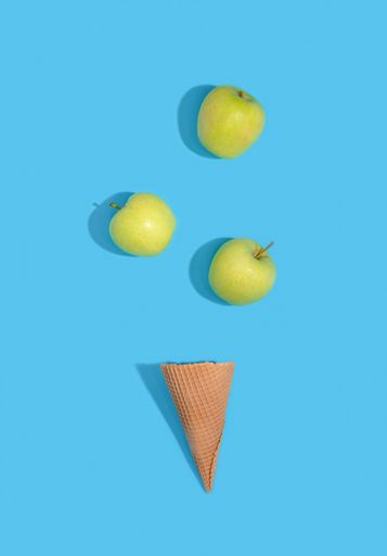A vertical shot of apples with ice cream waffle on a blue background