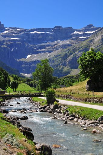 The river with a small bridge against the background of mountains. Cirque de Gavarnie, France.