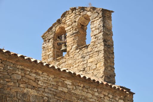 A low angle shot of an old stone building bell against a cloudless blue sky
