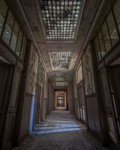 A vertical shot of the corridor of an old abandoned building with the decayed doors