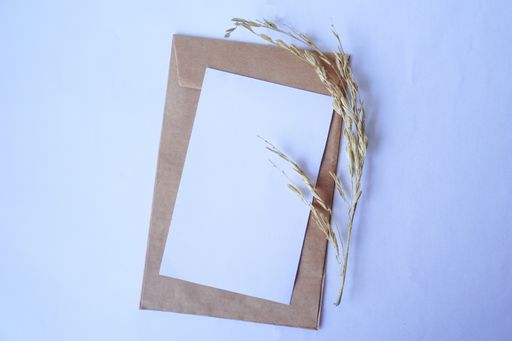A top view of a brown envelope and blank white letter with dried grass for mockup greeting seasonal concepts