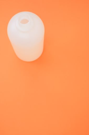 A vertical shot of a plastic bottle on an orange background