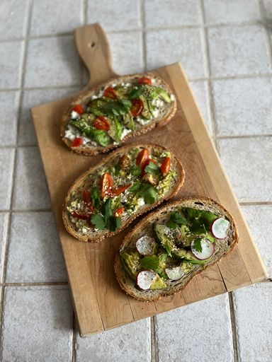 a high angle photo of avocado toast being served on a wooden cutting board