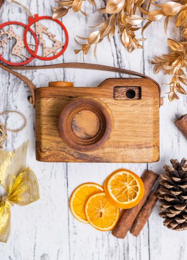 A vertical shot of a wooden camera toy on the table decorated with Christmas ornaments
