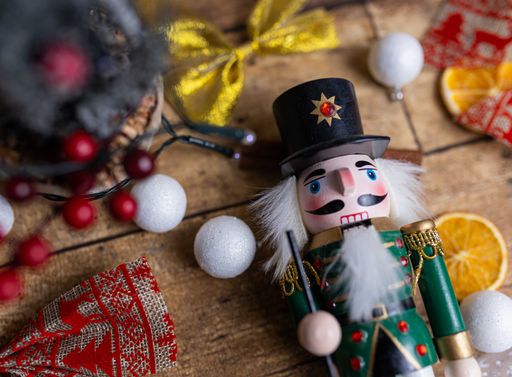 A wooden nutcracker toy on the table with Christmas decorations