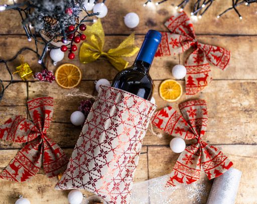A top view of a bottle of wine on the wooden table decorated with Christmas ornaments