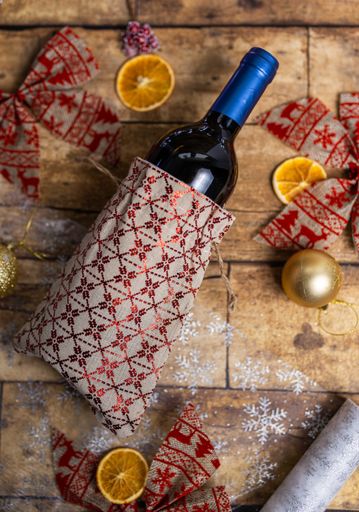 A vertical top view of a bottle of wine on the wooden table decorated with Christmas ornaments