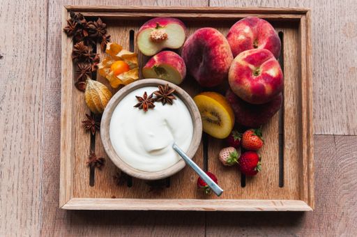 Wooden bowls filled with fresh nectarines, strawberries, kiwis, apples and a small bowl of yogurt