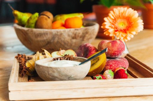 Wooden bowls filled with fresh nectarines, strawberries, kiwis, apples and a small bowl of yogurt