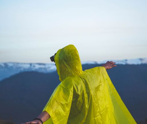 Man in a raincoat enjoying the rain on a hill