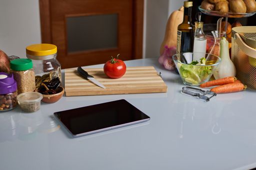 Fresh raw vegetables, spices and a tablet on a kitchen table