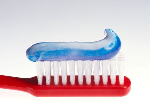 Toothbrush with blue toothpaste close-up on white background