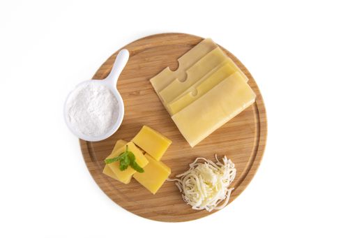 A top view of Swiss cheese slices and cubes on a wooden board isolated on a white background