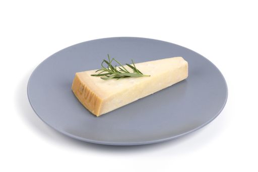 A closeup of a piece of parmesan cheese with rosemary isolated on a white background