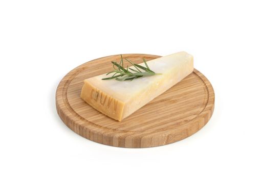 A closeup of a piece of parmesan cheese with rosemary on a board isolated on a white background