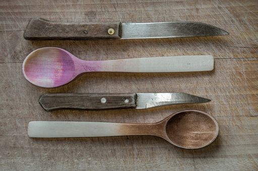 A high angle shot of old wooden knives and spoons on a wooden surface