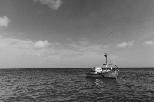 A black and white photo of a large boat floating in the open sea