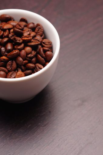 A vertical shot of a white cup filled with brown coffee beans